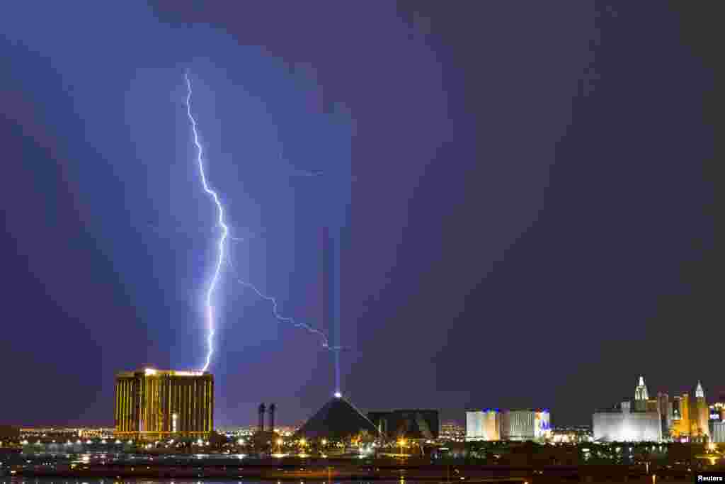 Petir menyambar di atas kasino Mandalay Bay (kiri) dan kasino Luxor (tengah) di kota Las Vegas, sementara badai bergerak melalui Las Vegas, negara bagian Nevada, AS.