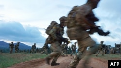 Des soldats traversent une route lors d'un exercice militaire de l'unité d'entraînement de l'armée britannique au Kenya (BATUK) avec les Forces de défense du Kenya (KDF) au ranch ol-Daiga, sur le plateau de Laikipia au Kenya, le 26 mars 2018.