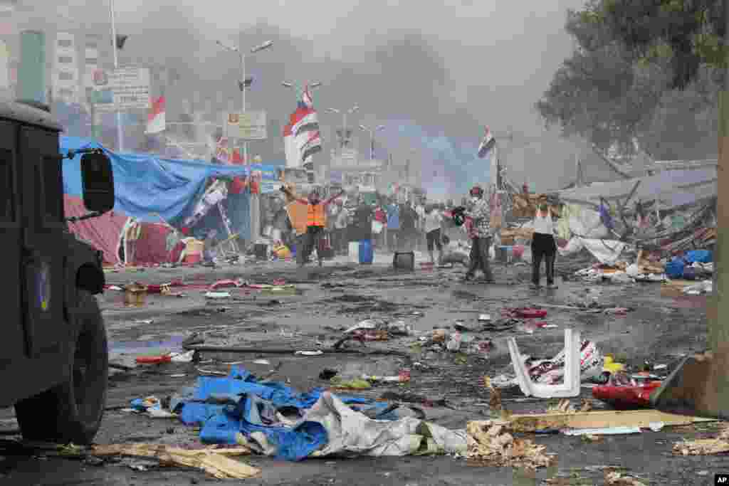 Supporters of ousted Islamist President Mohammed Morsi, stand among debris and smoke in background as they confront Egyptian security forces trying to clear the smaller of the two sit-ins, near the Cairo University campus in Giza, Cairo, Egypt, Wednesday,
