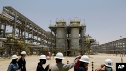 Des ingénieurs e Saudi Aramco et des journalistes devant l'usine de production de gaz naturel de Hawiyah, le 28 juin 2021, à Hawiyah, dans la province orientale de l'Arabie saoudite. 