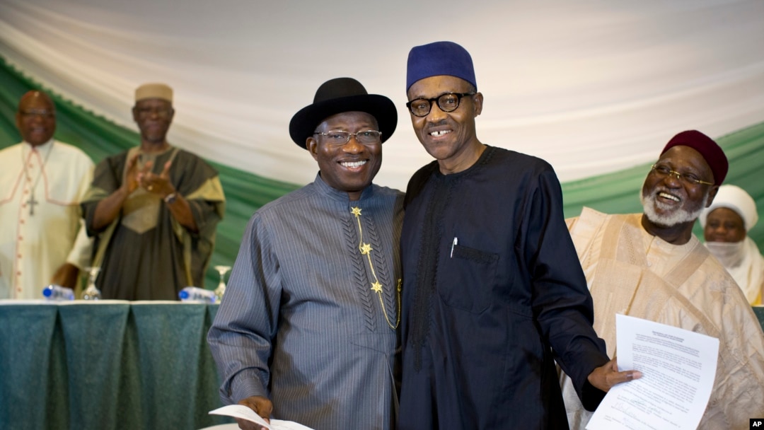Nigeria's President Goodluck Jonathan, center-left, and President-elect Gen. Muhammadu Buhari, center-right, hug and shake hands after signing a renewal of their pledge to hold peaceful "free, fair, and credible" elections, at a hotel in the capital. 