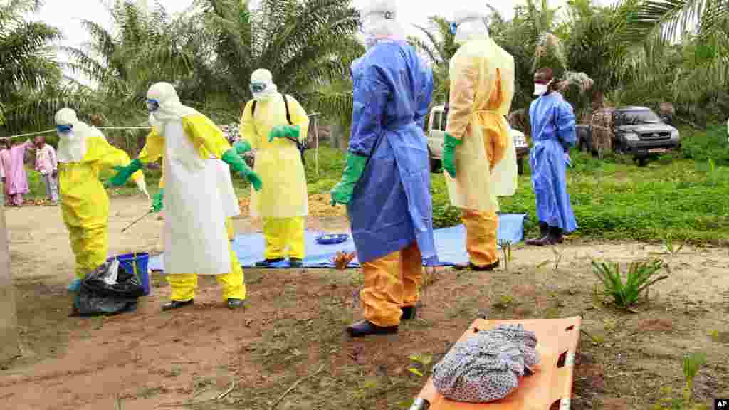 Des agents de la santé, vêtus d’équipement de protection contre le virus Ebola, transportent sur une civière la dépouille d'un enfant nouveau-né suspecté mort après avoir contracté l’épidémie, à Dubreka, Guinée, le 19 juin 2015