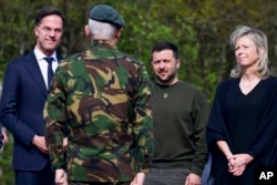 Belakang dari kiri, Perdana Menteri Belanda Mark Rutte, Presiden Ukraina Volodymyr Zelenskiy dan Kajsa Ollongren, Menteri Pertahanan Belanda berdiri di depan seorang prajurit selama kunjungan di pangkalan udara militer di Soesterberg, Belanda, 4 Mei 2023. (Yves Herman/Pool via AP)