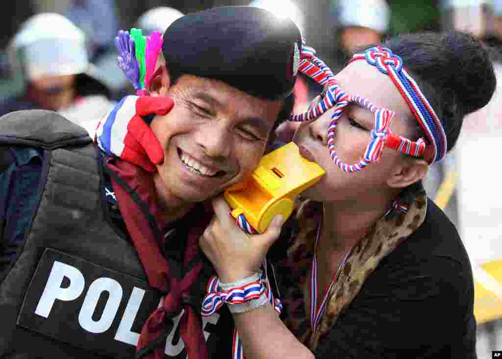 An anti-government protester blows a giant whistle to a riot police officer outside the headquarters of Prime Minister Yingluck Shinawatra's ruling Pheu Thai Party in Bangkok, Thailand.