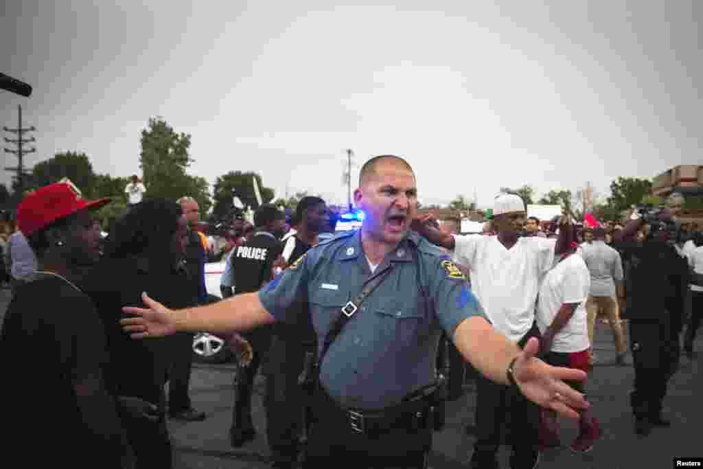 A Missouri State Highway Patrol officer clears a path to evacuate a woman needing medical attention, in Ferguson, Missouri, Aug. 14, 2014.