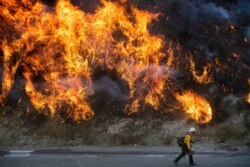 Flames from a backfire, lit by firefighters to stop the Saddleridge Fire from spreading, burn a hillside in Newhall, California, Oct. 11, 2019.