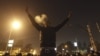 An anti-Morsi protester smokes a cigarette and and gestures in front of members of the Republican Guard blocking a road to the presidential palace in Cairo, Egypt, December 6, 2012. 