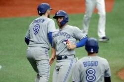 Brandon Drury (centro) de los Blue Jays de Torongo celebra con Danny Jansen (izq.) después de batear un sencillo que le permitió dos carreras en el juego con los Tampa Bay Rays, el domingo 26 de julio de 2020, en San Petersburgo, Florida.