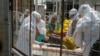 FILE - British health workers lift a newly admitted Ebola patient onto a wheeled stretcher in to the Kerry town Ebola treatment center outside Freetown, Sierra Leone, Dec. 22, 2014.