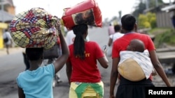 Une femme porte son enfant au dos et d'autres, leurs affaires sur une route de Bujumbura, Burundi, le 29 avril 2015.