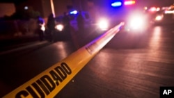 FILE - Police tape that reads in Spanish "Caution" marks off a crime scene where a man crashed his vehicle when he was shot while driving in Tijuana, Mexico.