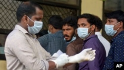 People in the southern Indian state of stand outside a hospital wearing masks to protect themselves against the Nipah virus, May 21, 2018.