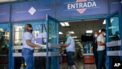 People wearing protective face masks amid the spread of the new coronavirus enter a grocery store that accepts U.S. dollars in Havana, Cuba, July 20, 2020.