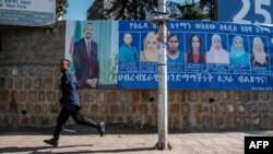 Mtu akimbia mbele ya mabango ya wagombea kwenye uchaguzi wa Ethiopia