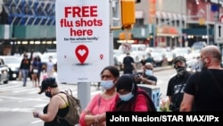 Un anuncio ofrece vacunas gratuitas contra la gripe mientras gente camina durante una protesta en Brooklyn, Nueva Yor, el 21 de agosto de 2020.