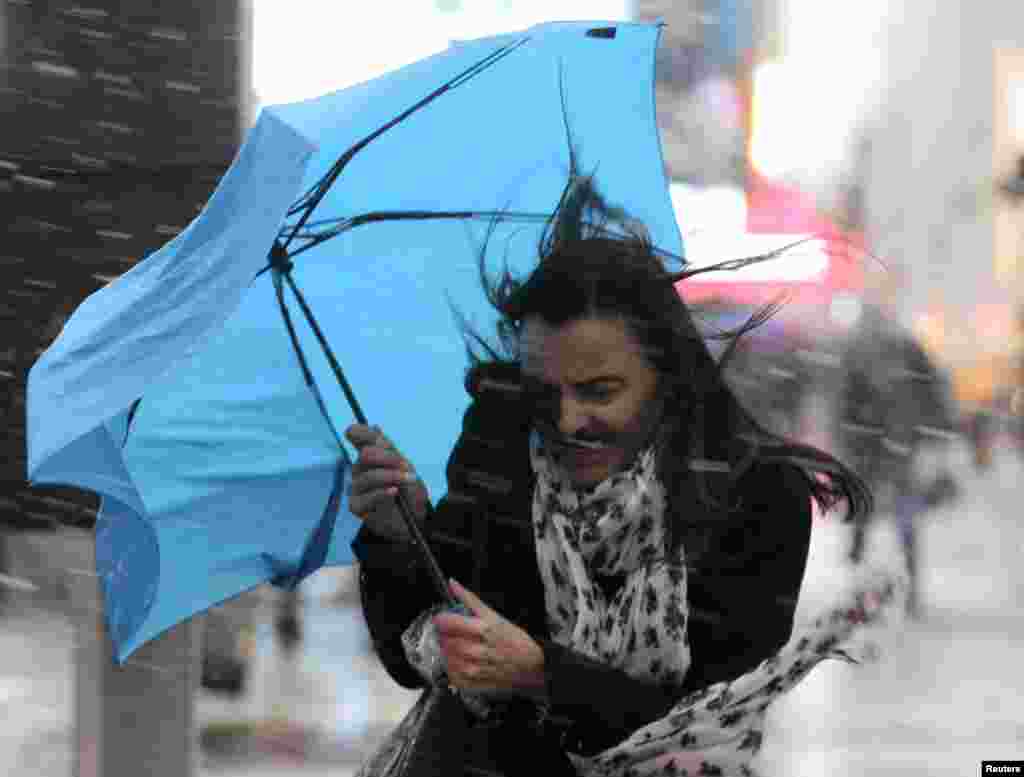 A woman struggles with her umbrella in the wind and snow in New York, November 7, 2012.
