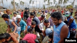 Para penyintas topan Haiyan bergegas mengambil bantuan air segar yang dikirimkan oleh helikopter militer AS ke desa mereka yang terisolasi di sebelah utara Tacloban (17/11).