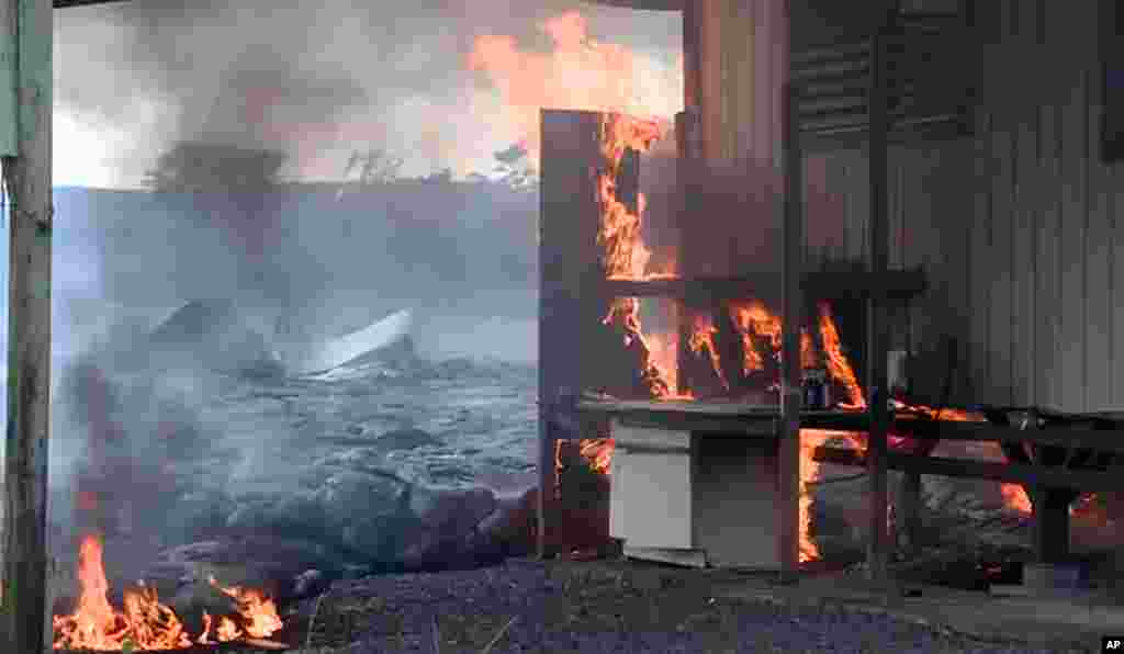Sur cette image prise par le comté d'Hawaii, la coulée de lave du volcan Kilauea brule une structure résidentielle le 11 novembre 2014,à Pahoa, Hawaii.