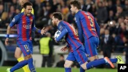 Lionel Messi de Barcelone, au centre, court, balle en main, en compagnie de ses co-équipiers Neymar, à gauche, et Gerard Piqué, après son but sur penalty lors d’un match de la Ligue des champions entre le FC Barcelone et Paris Saint Germain au stade Camp 