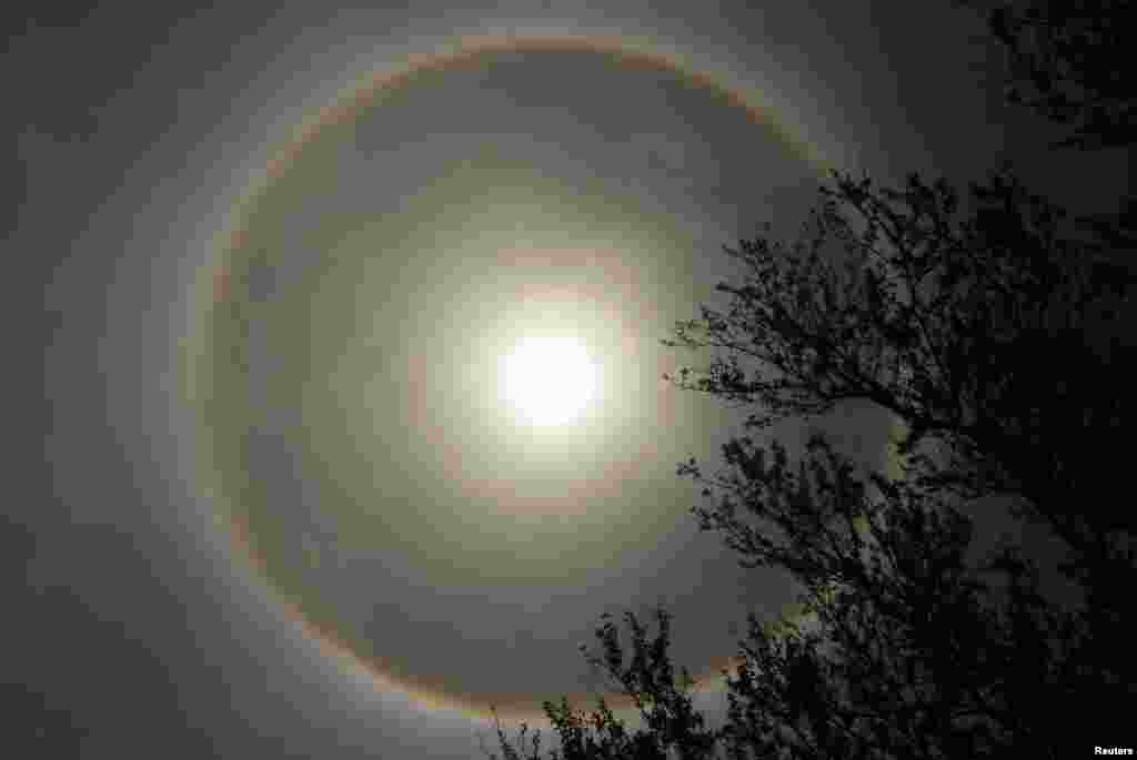 Sebuah fenomena atmosfer yang dikenal sebagai "matahari semu" atau parhelion (semacam "halo" pada matahari) terlihat di La Paz, El Savador, 26 Juni 2013. Halo yang mengelilingi matahari muncul karena pembiasan cahaya matahari oleh kristal es kecil pada atmosfer.