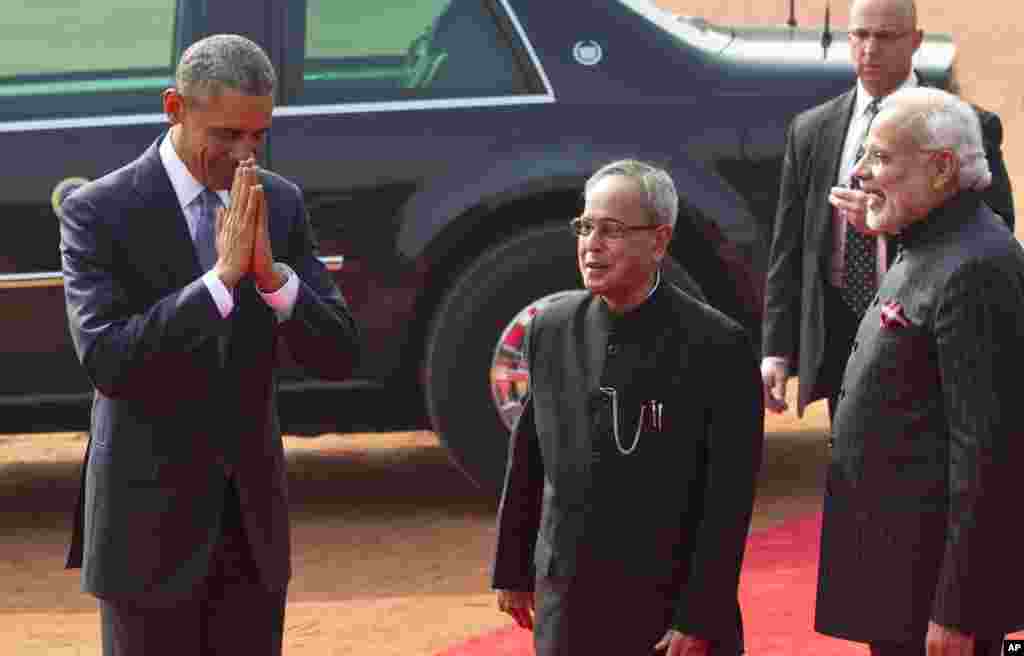 U.S. President Barack Obama folds his hands in a traditional Indian greeting gesture, as Indian President Pranab Mukherjee, center, and Prime Minister Narendra Modi laugh during a ceremonial reception at the Indian presidential Palace in New Delhi, Jan. 25, 2015.