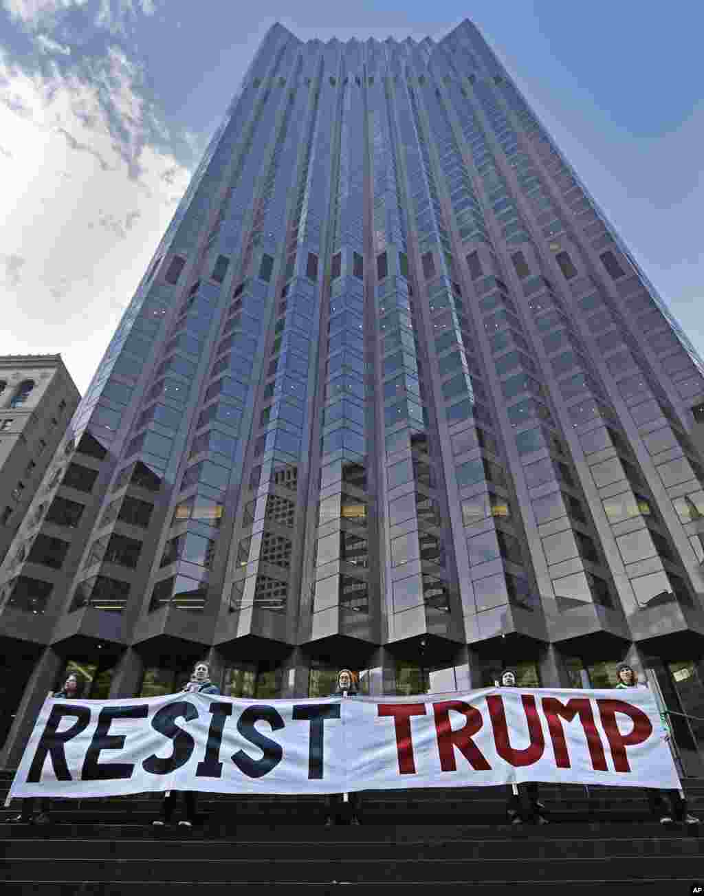 Protestors rally at the entrance of 555 California St., the only partially Trump-owned building in San Francisco, on Friday, Jan. 20, 2017. Protests against the inauguration of President Donald Trump are underway in California. Demonstrators gathered in the rain Friday at San Francisco's Civic Center Plaza and across the bay in Oakland at the Ronald Dellums Federal Building