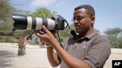 Wartawan Somalia Mohamed Mohamud memegang kameranya saat meliput di komplek Rumah Sakit Medina di Mogadishu, Somalia. Mohamud terbunuh saat melaksanakan tugas pada tahun 2013. (Foto:dok)