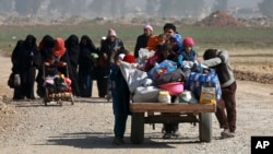 FILE - Iraqi civilians walk toward Iraqi security forces after fleeing their homes because of fighting between government forces and Islamic State militants, on the western side of Mosul, Iraq, March 9, 2017.