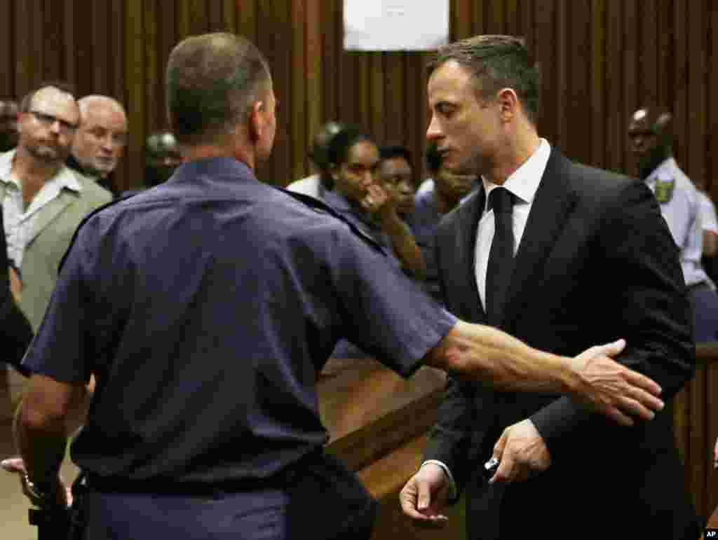 Oscar Pistorius, à droite, a été emmené en prison à la sortie de l'audience. mardi le 21 octobre 2014.