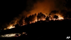 Firefighters watch from their fire trucks as wildfires continue to burn, Oct. 12, 2017, near Calistoga, California. 