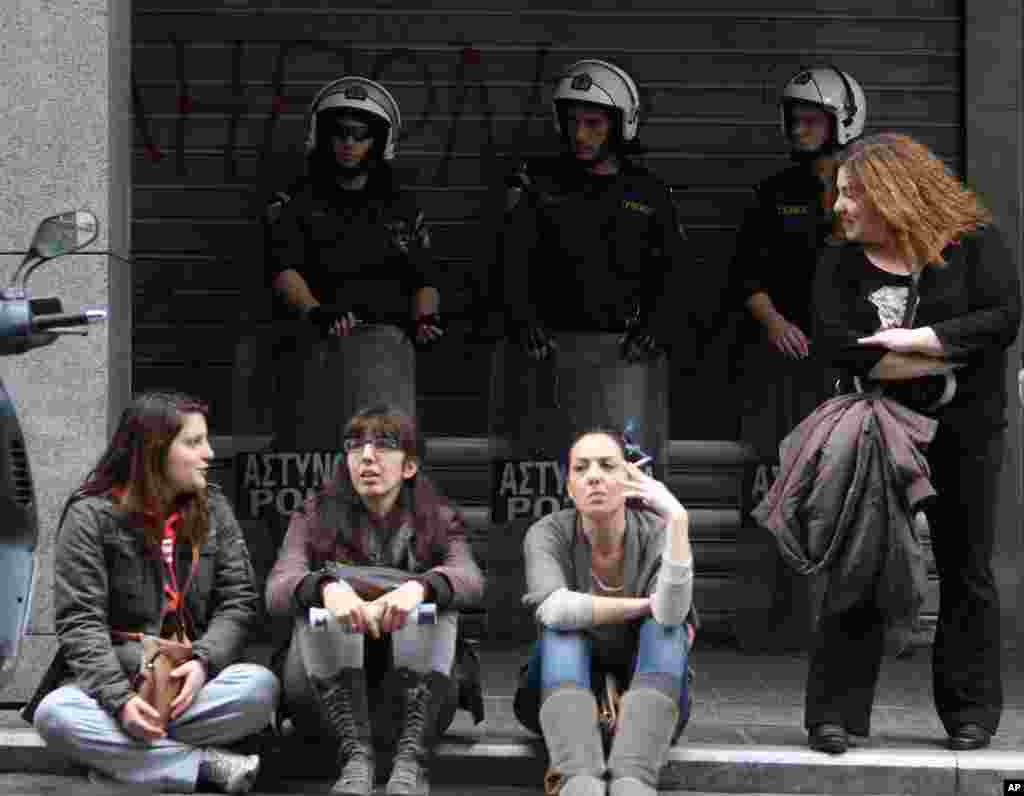 Bank of Cyprus employees sit in front of riot police during a protest outside Greece's Finance Ministry as the bank remains closed for third day in central Athens, March 21, 2013.
