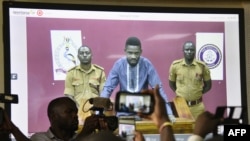 
Un musicien ougandais devenu politicien, Robert Kyagulanyi, au centre, alias Bobi Wine, se rend au tribunal par vidéoconférence à Kampala, le 2 mai 2019.
