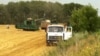 A John Deere combine harvests, threshes and pumps wheat into a waiting truck on fields managed by UkrLand Farming, July 21, 2012. Wheat from these fields may end up in Chinese bread next year. (VOA/J. Brooke)