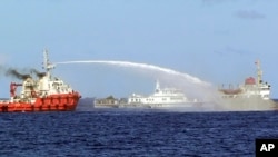 In this photo released by Vietnam Coast Guard, a Chinese ship, left, shoots water cannon at a Vietnamese vessel May 7, 2014. Vietnam tried to stop Beijing from setting up an oil rig in the South China Sea. (AP Photo/Vietnam Coast Guard)
