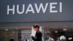 People walk past a Huawei retail store in Beijing, June 30, 2019. 