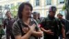 Thailand Politics: FILE - Sombat Boonngam-anong gestures a sign of freedom while arriving at the military court in Bangkok, Thailand, June 12, 2014.