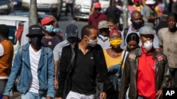 Des piétons portant des masques faciaux pour se protéger du coronavirus marchent dans la rue au centre-ville de Johannesburg, en Afrique du Sud, le 11 mai 2020. (Photo AP)