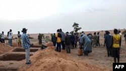 Des officiels et des habitants se tiennent près de tombes fraîchement creusées le 11 juin 2019 dans un village Dogon au Mali après l'attaque de l'ethnie Dogon le 9 juin 2019.