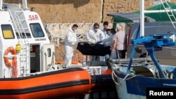 Petugas layanan darurat membawa jenazah korban kapal migran yang terbakar di lepas pantai Crotone, ke dermaga Le Castella , Italia, 30 Agustus 2020.
