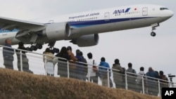 Quelques spectateurs en train de contempler un avion japonais atterrir à l'aéroport international de Narita, à partir du parc de Sakuranoyama, à l'est de Tokyo, 14 mars 2015. 