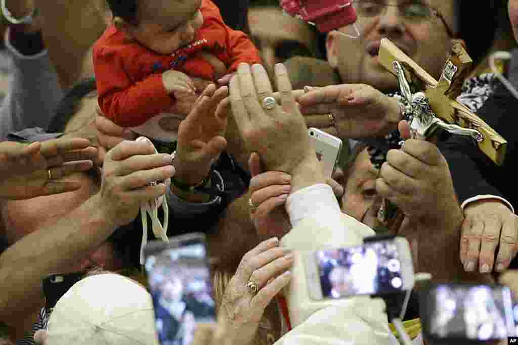 Faithful reach for Pope Francis' hand, center, during an audience with Roma, Sinti and others itinerant group members, at the Vatican.