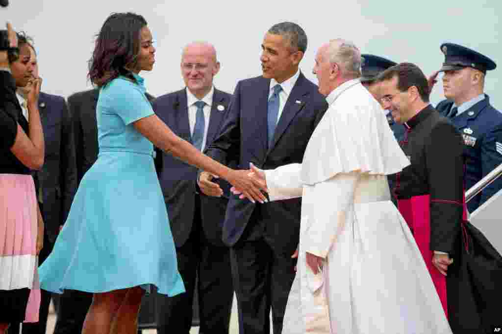 Ibu Negara Michelle Obama, didampingi suaminya Barack, menyambut Paus Fransiskus saat tiba di Pangkalan Angkatan Udara Andrews, Maryland (22/9). (AP/Andrew Harnik)