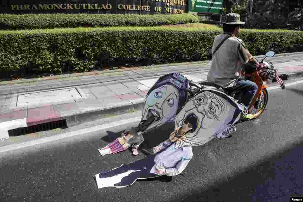 Seorang pengunjuk rasa anti-pemerintah mengendarai sepeda motor yang menarik karikatur yang menggambarkan Perdana Menteri Thailand Yingluck Shinawatra dan kakaknya Thaksin dalam unjuk rasa di pusat kota Bangkok.