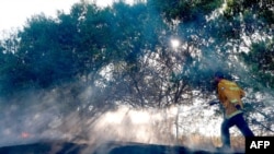 An Israeli fireman extinguishes a fire in a field near the Israel-Gaza border that was reportedly caused by an incendiary balloon launched from the Gaza Strip, on Aug. 24, 2020.