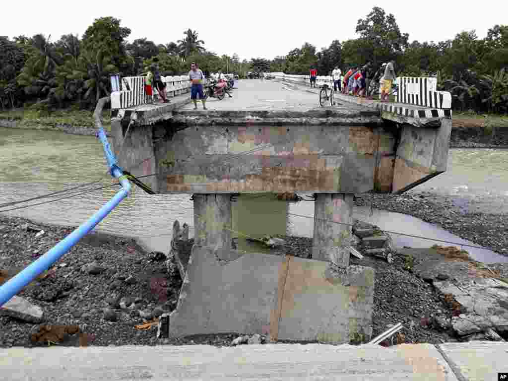 Des gens rassemblés sur un pont détruit par l'inondation provoquée par la tempête tropicale Tembin, le 24 décembre 2017 aux Philippines.