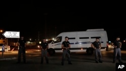 Israeli police stand guard while Israeli Prisons Authority vans pass carrying Palestinian prisoners to Gaza through the Erez border crossing between the Gaza Strip and Southern Israel, Aug. 13, 2013. 