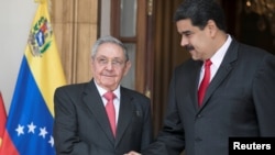 FILE - Cuba's Raul Castro (L) shakes hands with Venezuela's Nicolas Maduro in Caracas, Venezuela, March 5, 2018.