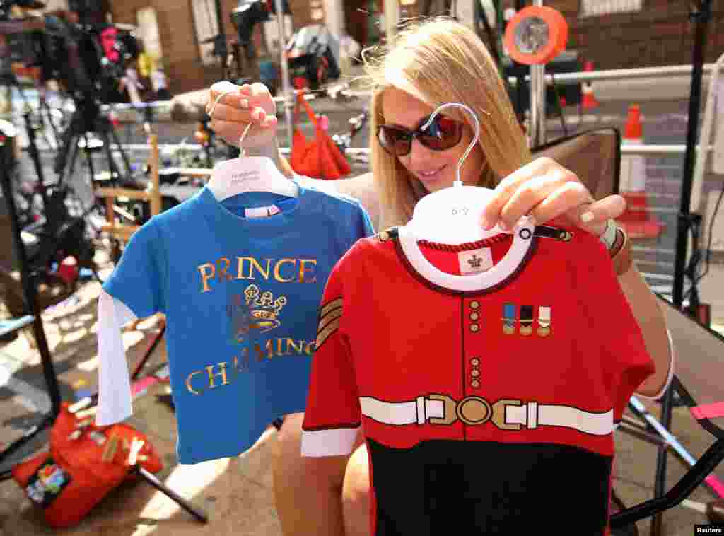 Reporter dari media Amerika memilih baju bayi mana yang akan diperlihatkan di kamera (15/7) di luar Sayap Lindo, Rumah Sakit St. Mary's, tempat Duchess of Cambridge akan melahirkan di London. (Reuters/Olivia Harris)