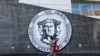 Un hombre camina frente al emblema de The City College of New York en Manhattan. 