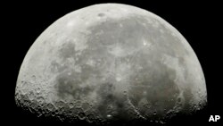 The International Space Station, center, passes in front of the Moon in its Earth orbit as photographed from Salgotarjan, Hungary, Thursday, July 5, 2018. 